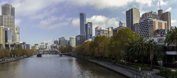 River amidst buildings in city against sky