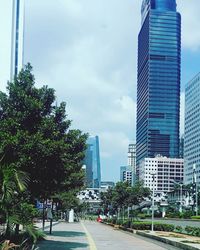 City street by modern buildings against sky