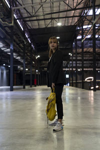 Portrait of businesswoman with backpack standing at railroad station