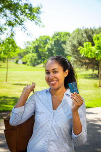 Portrait of smiling young woman against trees