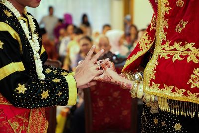 Asian muslim couple holding and putting ring each other hand in minangkabau wedding ceremony.