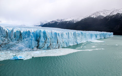 Scenic view of glacier with mountain range in the background