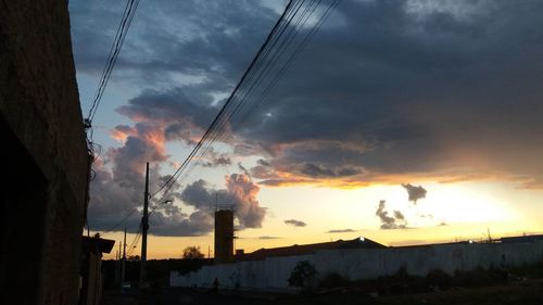 Low angle view of silhouette electricity pylon against sky during sunset