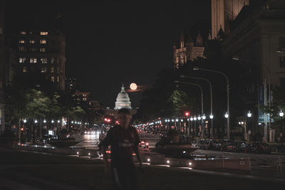 Illuminated city street amidst buildings at night