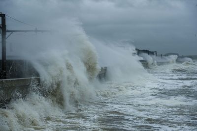 Waves splashing on shore against sky