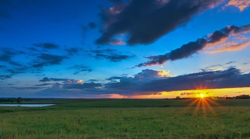 Scenic view of grassy field against cloudy sky