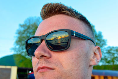 Close-up of young man wearing sunglasses against clear sky