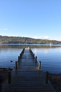 Pier over lake against clear blue sky