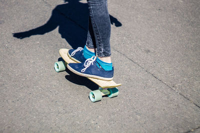 Low section of woman skateboarding on road