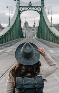 Rear view of young woman wearing backpack, standing on liberty bridge in budapest