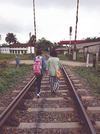 Rear view of people walking on railroad tracks