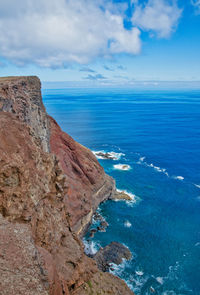 Rock formations by sea against blue sky