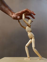 Close-up of hand over figurine on table