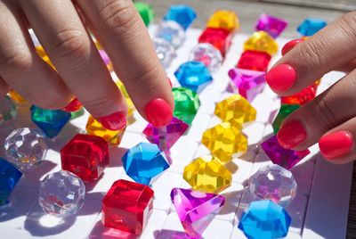 Cropped hands of woman holding multi colored diamonds