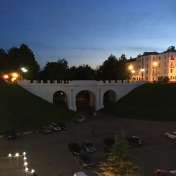 Road by illuminated city against sky at night