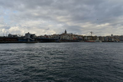 Sea by buildings against sky in city