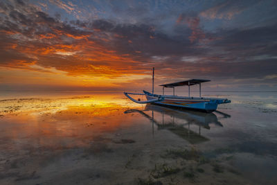Boat moored on sea against sky during sunset