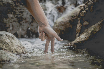 Low section of person standing on rock in water