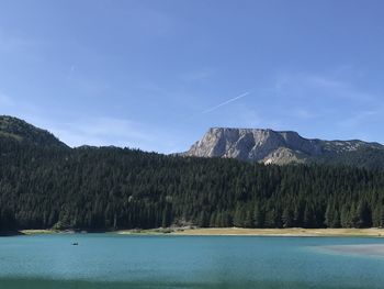 Scenic view of lake and mountains against blue sky