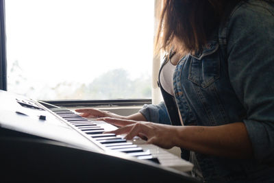 Midsection of woman playing piano at home