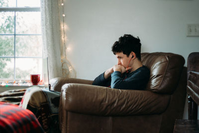 Young man sitting on sofa at home