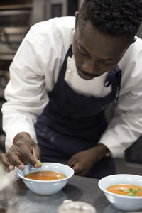 Chef garnishing soup with basil leaves in restaurant kitchen