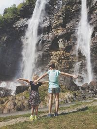 Rear view of girls standing against waterfall