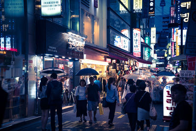 People on street by building in city at night