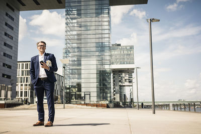 Mature businessman with cell phone standing outdoors