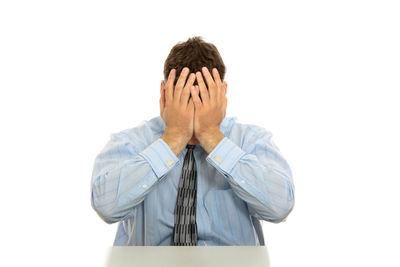 Portrait of man covering face against white background