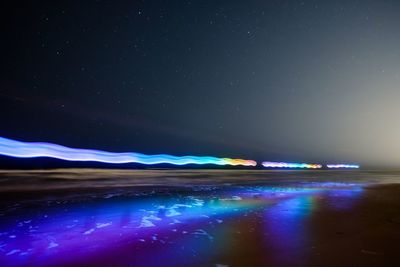 Light trails against blue sky at night