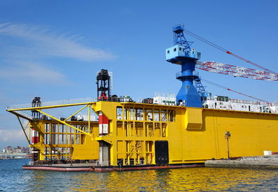 Crane by sea against blue sky