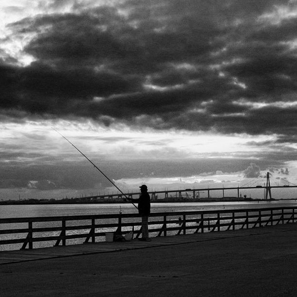 sky, cloud - sky, water, railing, cloudy, standing, silhouette, cloud, full length, connection, sea, rear view, lifestyles, men, leisure activity, bridge - man made structure, built structure, weather