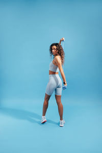 Woman exercising with resistance band against blue background