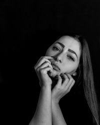 Close-up portrait of sad young woman against black background