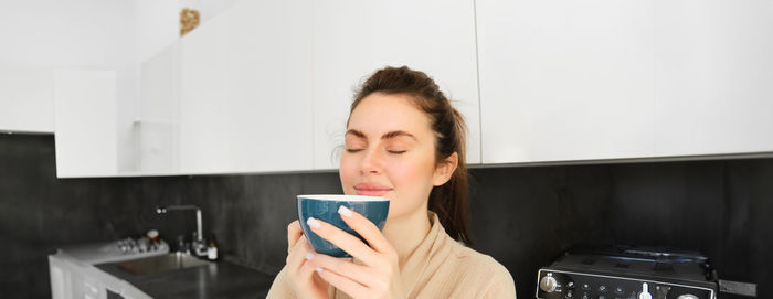 Portrait of young woman using mobile phone at home