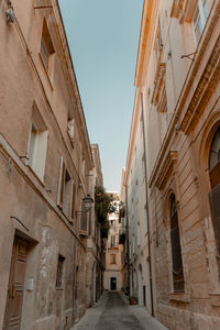Low angle view of narrow alley amidst buildings against sky