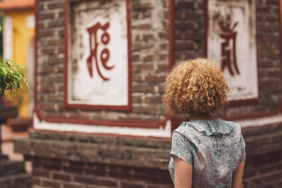 Rear view of woman standing against wall