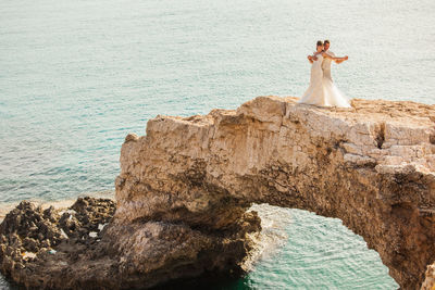 Woman standing on rock by sea