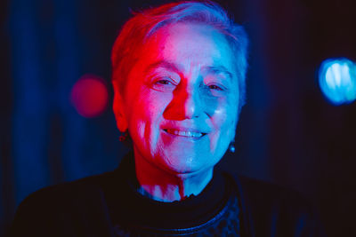 Colroful close-up portrait of senior woman against black background