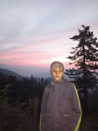 Portrait of boy standing in forest during sunset