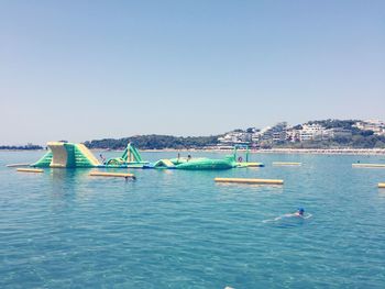 Boats in sea against clear blue sky