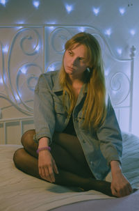 Young woman looking down while sitting on wall