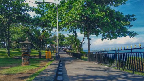 Footpath by street against sky