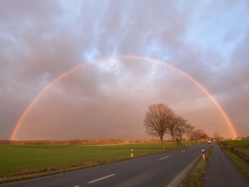 Scenic view of rainbow over road against sky