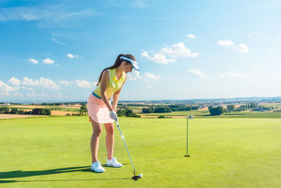 Full length of woman playing golf against sky