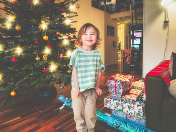 Portrait of boy standing by christmas tree