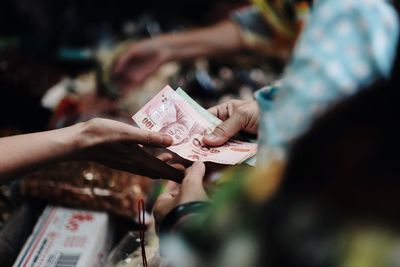 Cropped hands of costumer giving paper currency to vendor at market