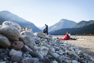 Man in bivouac looking at friend packing backpack on vacation, karwendel mountains, bavaria, germany