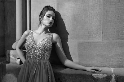 Portrait of young woman standing against wall